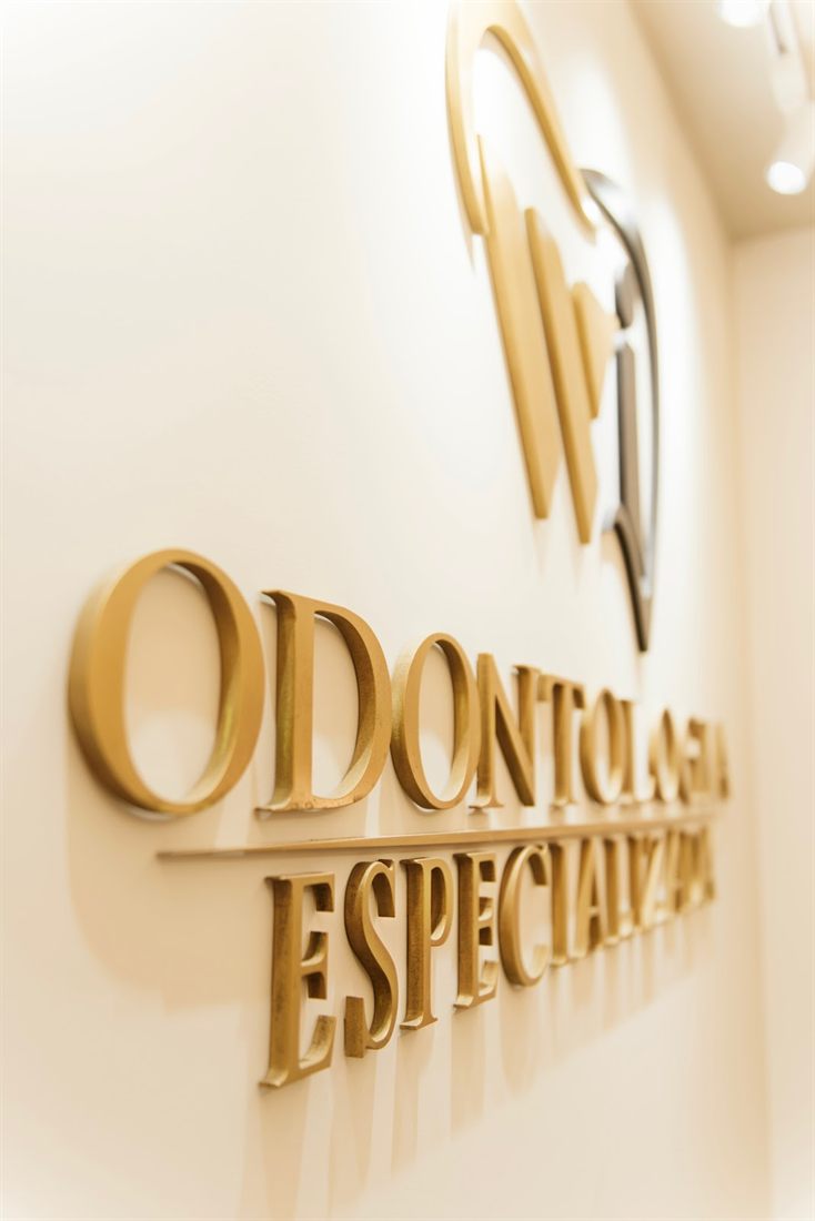 Letreiro dourado WI Odontologia Especializada na parede da clínica